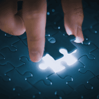 Fingers putting last piece of jigsaw in place